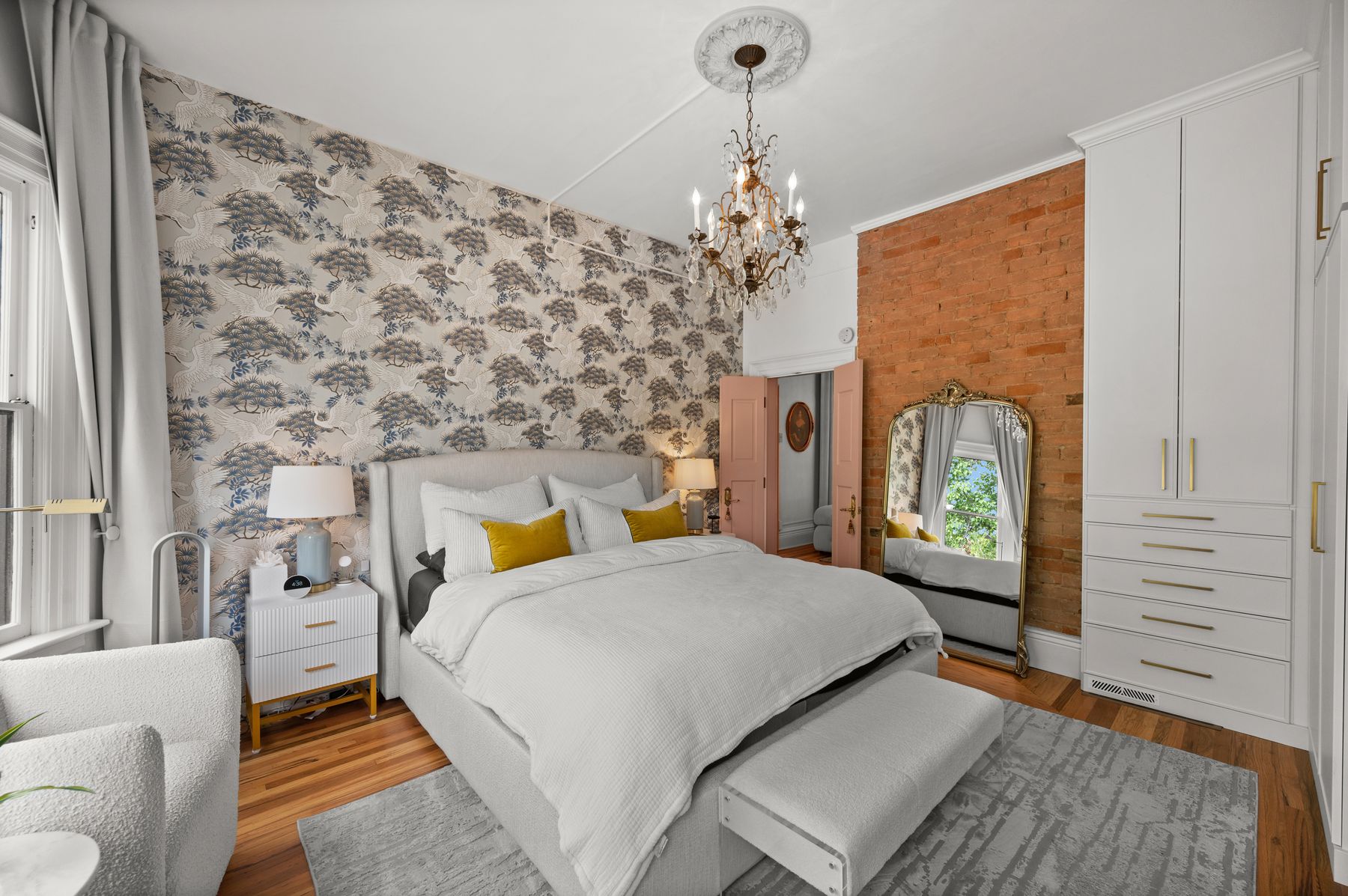 Primary bedroom with crane wallpaper, exposed brick and blush pink doors