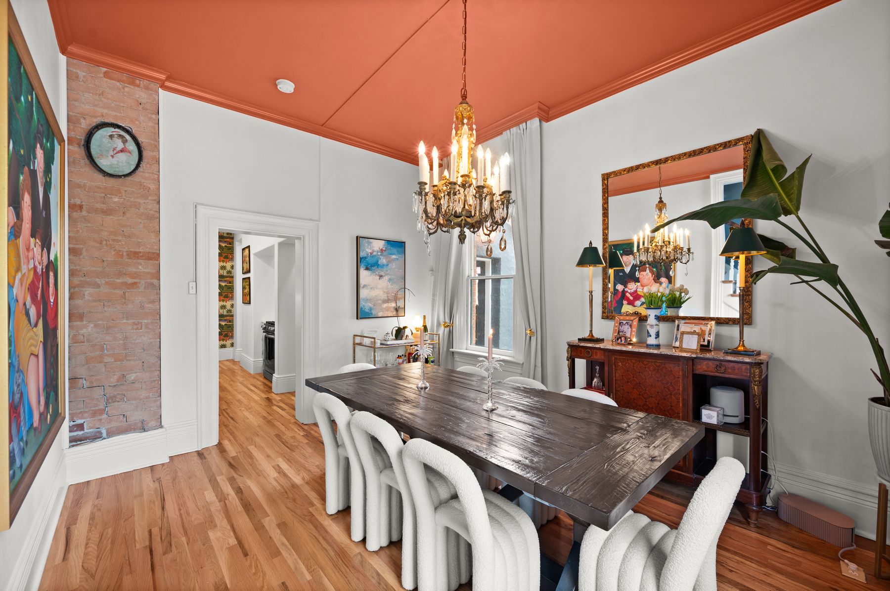 Dining room with terracotta ceiling, brass chandelier and Botero painting