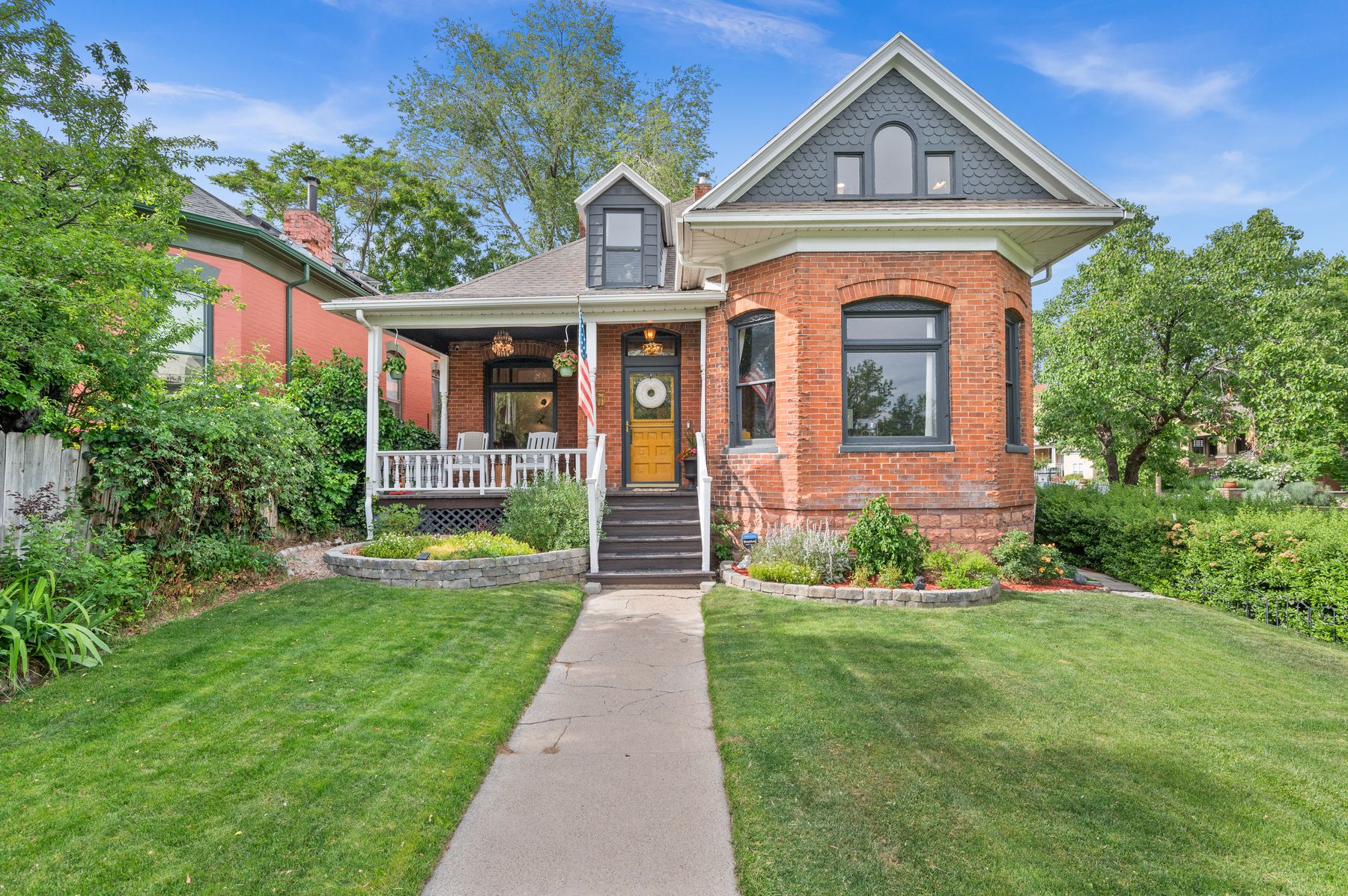 The Schettler House — brick Victorian with slate fish-scale gable and marigold front door