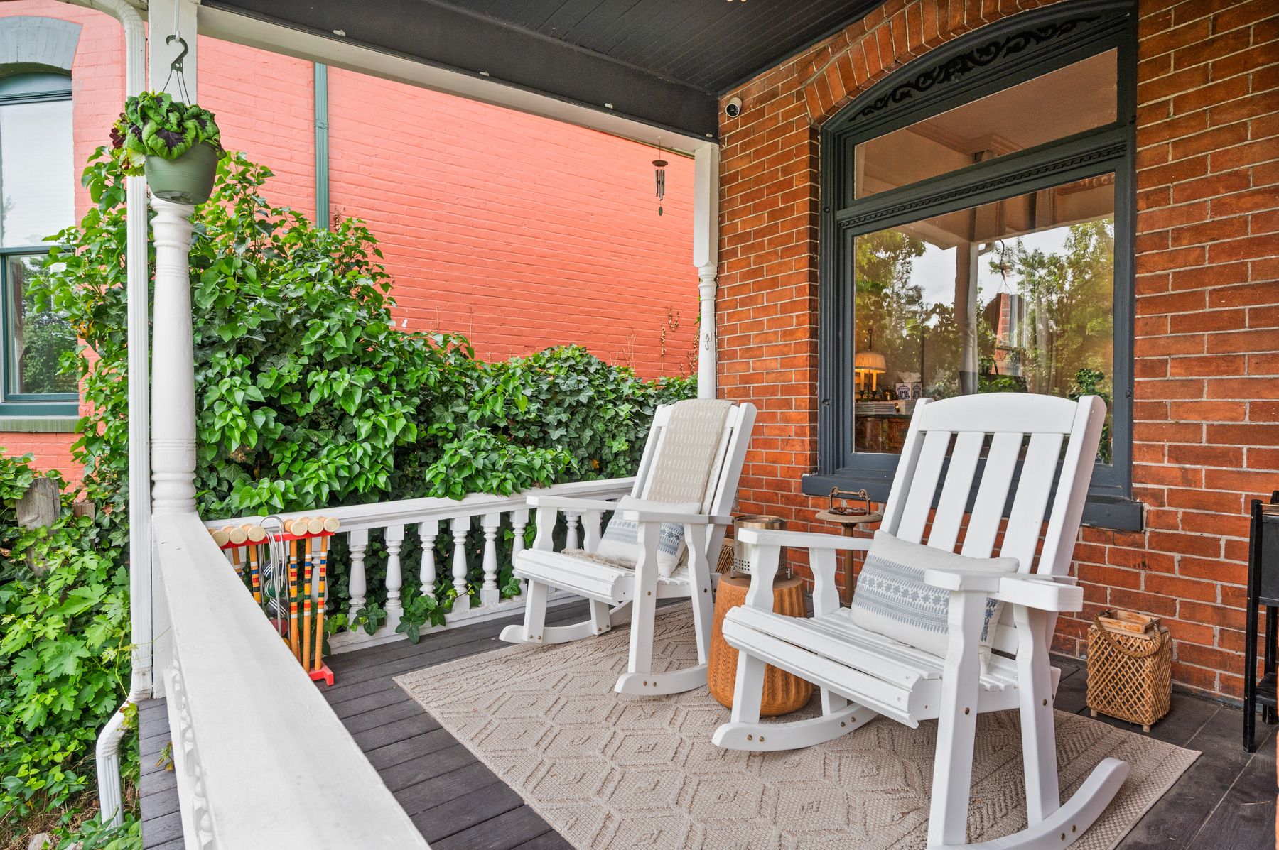 Front porch with white rockers, ivy and a vintage croquet set